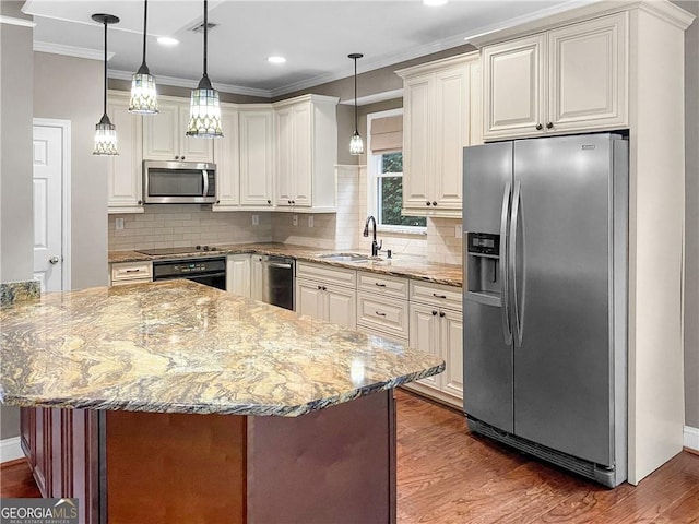 kitchen featuring wood finished floors, light stone countertops, appliances with stainless steel finishes, and a sink