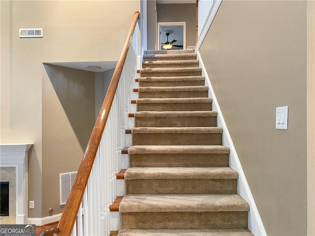 staircase with visible vents, baseboards, and a premium fireplace