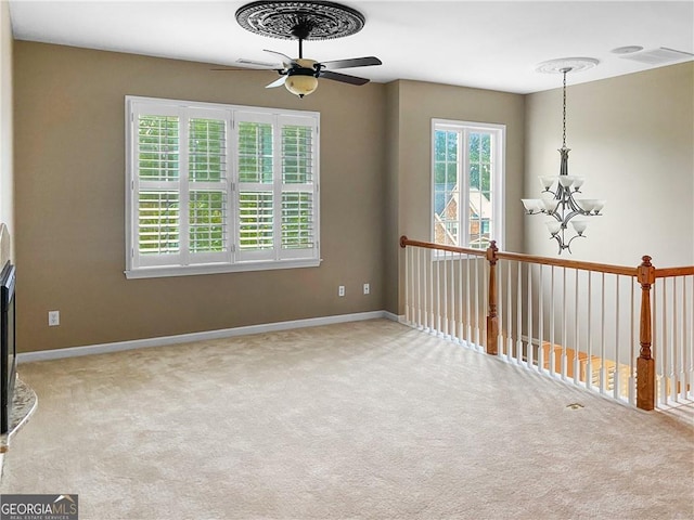 empty room with visible vents, ceiling fan with notable chandelier, baseboards, and carpet