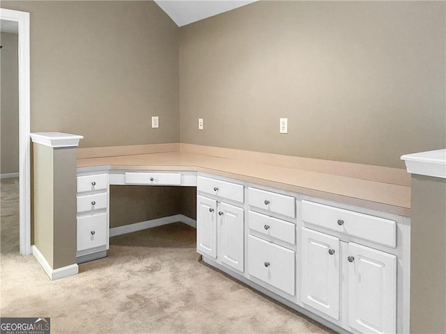 unfurnished office with built in desk, light colored carpet, and baseboards