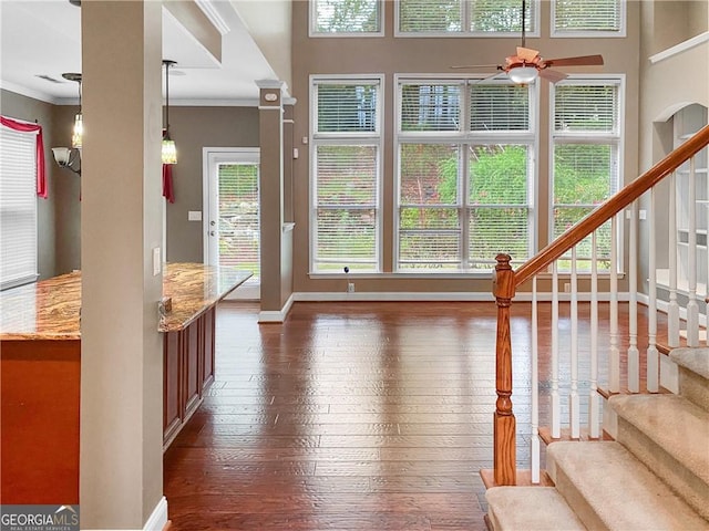 living area featuring plenty of natural light, dark wood-type flooring, ceiling fan, and ornamental molding