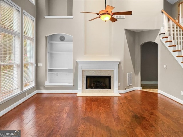 unfurnished living room with visible vents, built in features, hardwood / wood-style floors, a fireplace, and baseboards