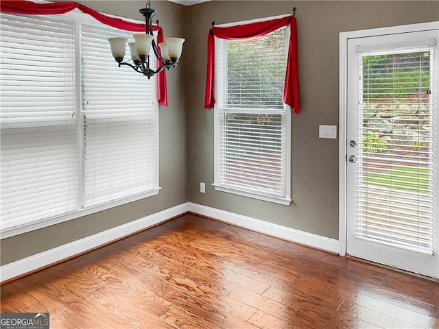 interior space with a notable chandelier, baseboards, and wood finished floors