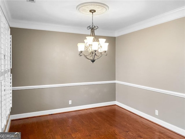 unfurnished room featuring a notable chandelier, crown molding, baseboards, and wood finished floors