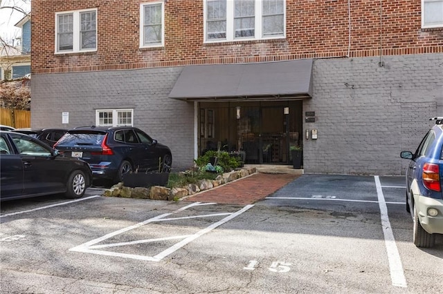 entrance to property with uncovered parking and brick siding