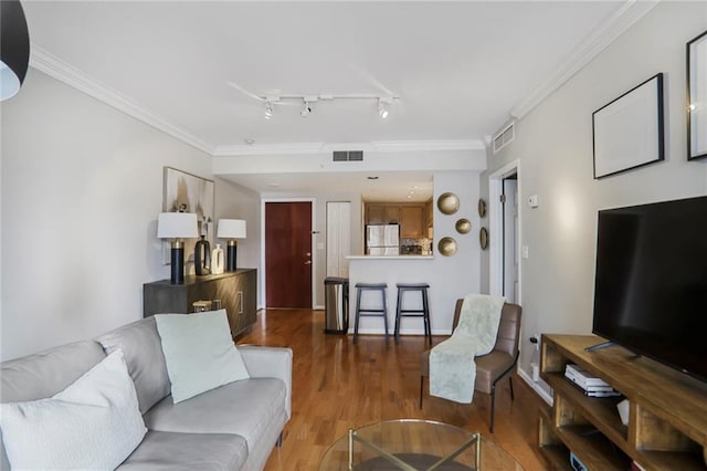 living room featuring visible vents, crown molding, track lighting, and wood finished floors