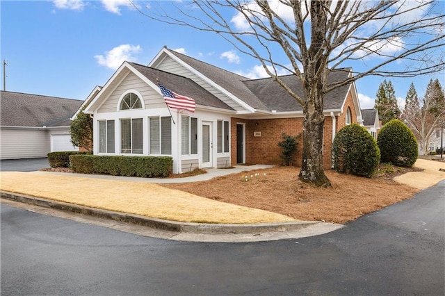 view of front facade featuring brick siding and a shingled roof