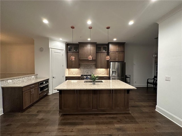 kitchen featuring appliances with stainless steel finishes, decorative light fixtures, dark brown cabinets, and dark wood-type flooring