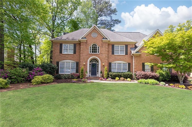 colonial inspired home with brick siding and a front lawn