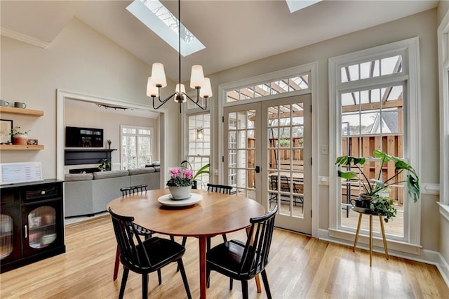 dining room with a skylight, light wood finished floors, french doors, a chandelier, and lofted ceiling