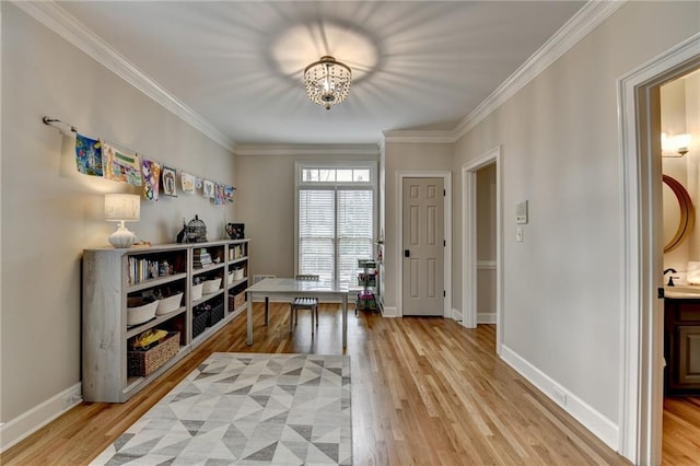 entryway featuring light wood finished floors, a chandelier, ornamental molding, and baseboards
