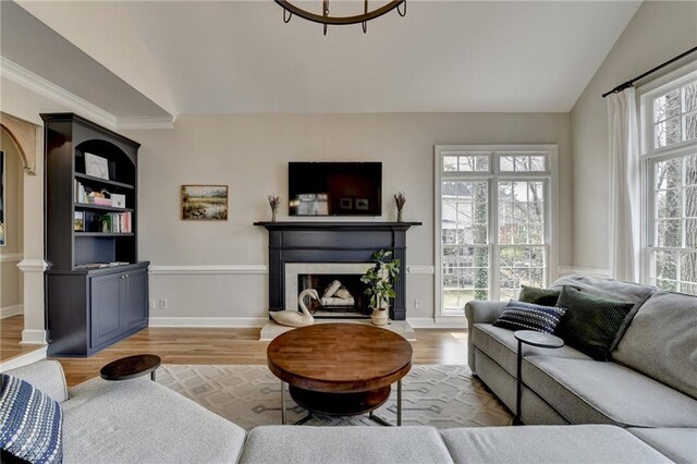 living room with vaulted ceiling, light wood-style floors, a fireplace, and baseboards