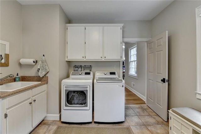 laundry room with washer and clothes dryer, cabinet space, baseboards, and light tile patterned floors