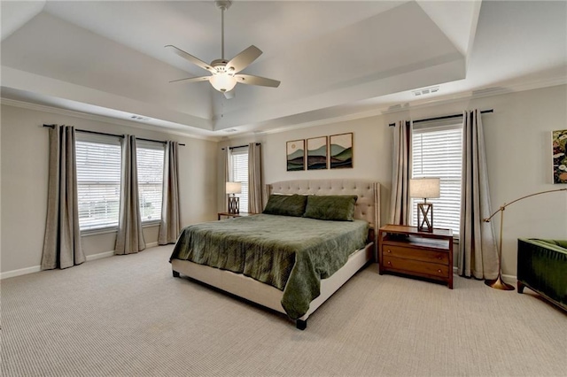 bedroom featuring a tray ceiling, light colored carpet, baseboards, ornamental molding, and a ceiling fan