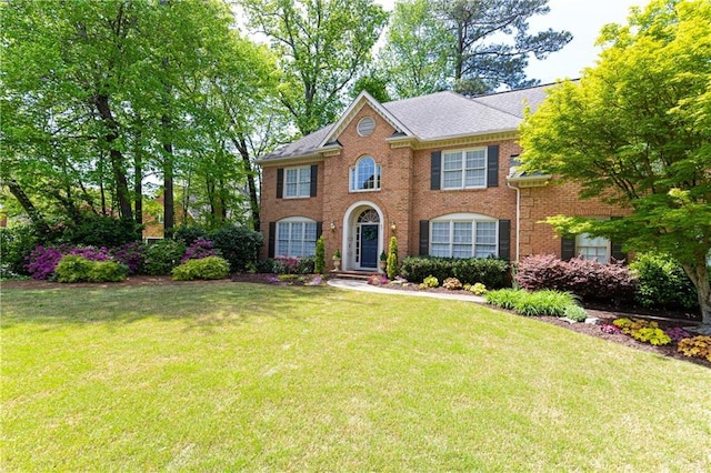colonial home with brick siding and a front yard