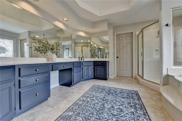 bathroom with a tray ceiling, a shower stall, vanity, a bath, and tile patterned floors