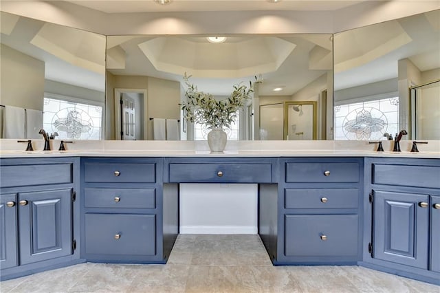 full bath with a tray ceiling, a stall shower, double vanity, and tile patterned flooring