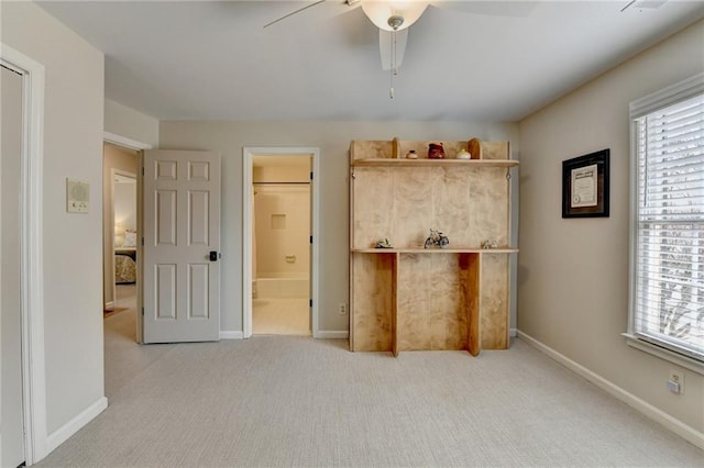 unfurnished bedroom featuring carpet floors, baseboards, connected bathroom, and a ceiling fan