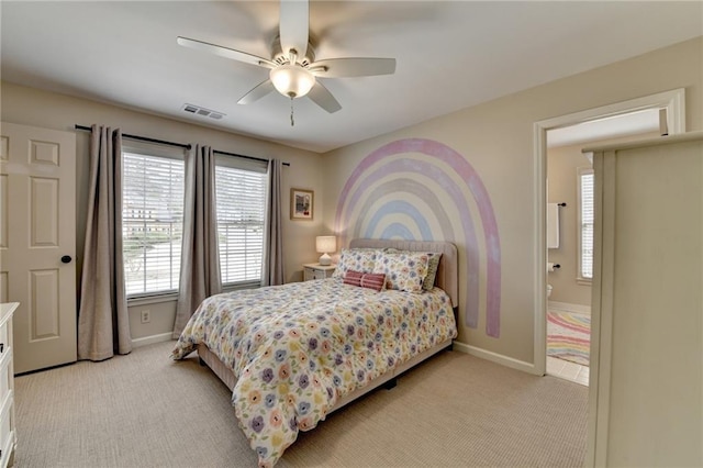 bedroom with light colored carpet, baseboards, a ceiling fan, and ensuite bath