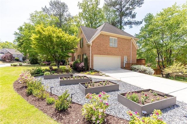 view of front of house with a garden, an attached garage, concrete driveway, and brick siding