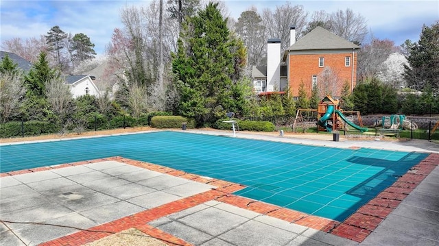 view of pool with a covered pool, a playground, fence, and a patio