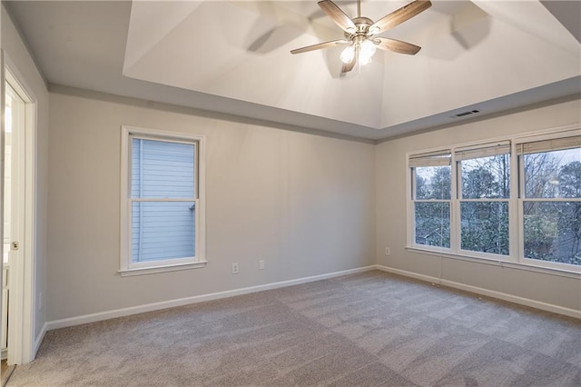 empty room with lofted ceiling, a tray ceiling, light colored carpet, and ceiling fan