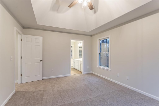 carpeted empty room featuring ceiling fan, a tray ceiling, and vaulted ceiling