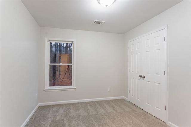 unfurnished bedroom featuring light colored carpet and a closet