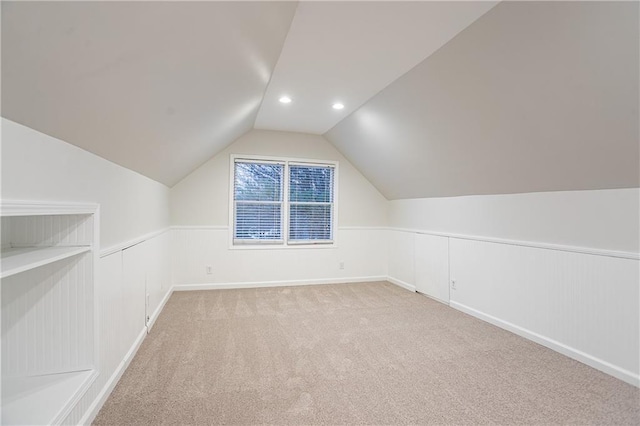 bonus room with lofted ceiling and light carpet