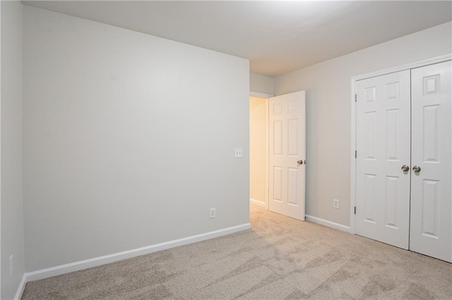 unfurnished bedroom with light carpet and a closet