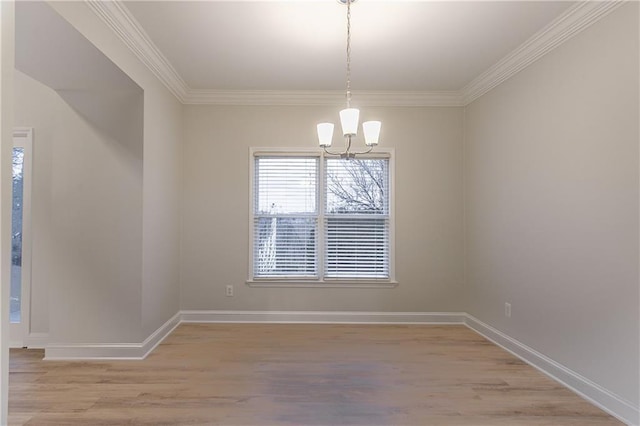 spare room with an inviting chandelier, crown molding, and light hardwood / wood-style floors