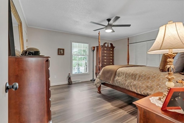 bedroom with ceiling fan, a textured ceiling, crown molding, dark hardwood / wood-style floors, and a closet