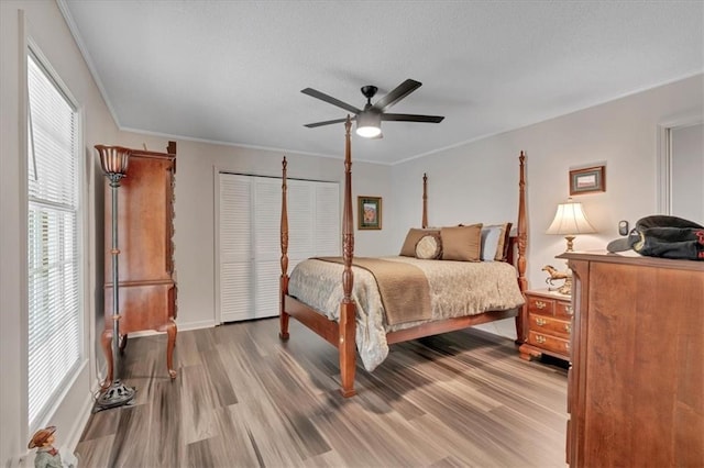 bedroom with a closet, ceiling fan, crown molding, and wood-type flooring