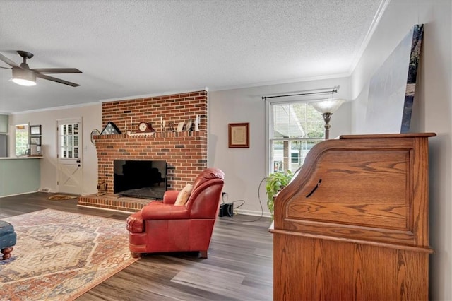 living room with crown molding, wood-type flooring, a textured ceiling, and a brick fireplace