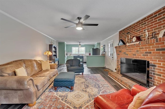 living room featuring ceiling fan, ornamental molding, dark hardwood / wood-style flooring, and a brick fireplace