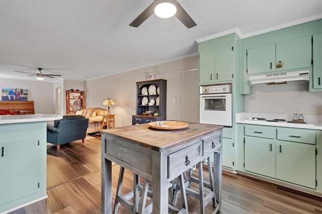 kitchen featuring white appliances, green cabinetry, a textured ceiling, dark hardwood / wood-style flooring, and crown molding