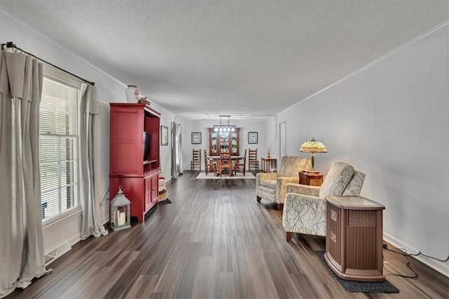 living area featuring ornamental molding, a textured ceiling, a notable chandelier, and dark hardwood / wood-style floors