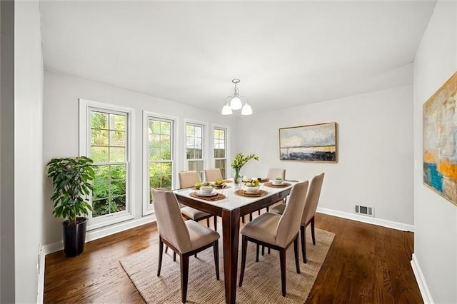 dining area with dark hardwood / wood-style floors and a notable chandelier