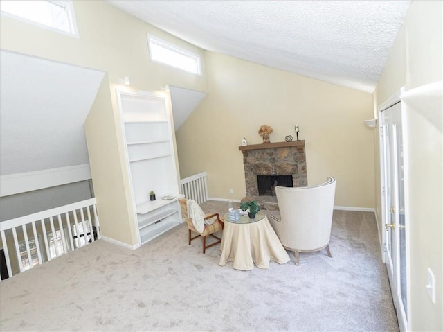 living area with lofted ceiling, a stone fireplace, carpet floors, and a textured ceiling