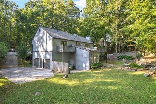 rear view of property with a garage, a lawn, a sunroom, and a balcony