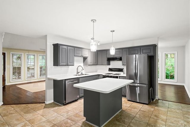 kitchen with appliances with stainless steel finishes, pendant lighting, sink, gray cabinetry, and a center island