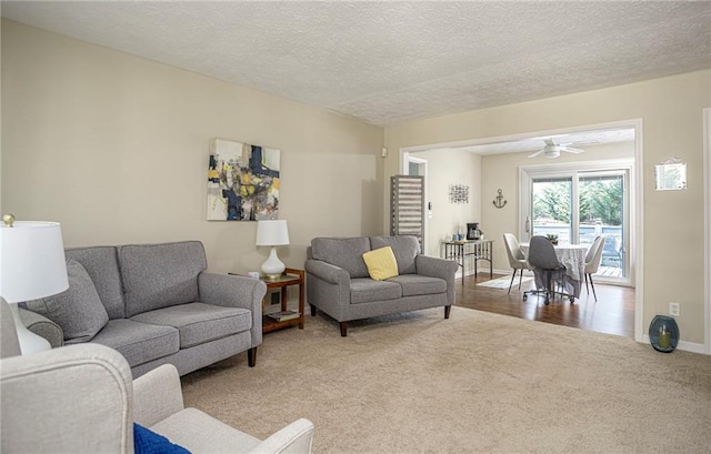 living room with a textured ceiling, ceiling fan, and carpet floors