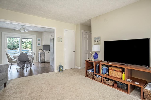 living room featuring ceiling fan, a textured ceiling, and carpet floors