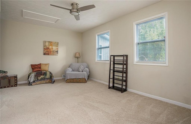 living area with ceiling fan, light colored carpet, and a healthy amount of sunlight