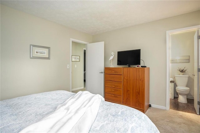 carpeted bedroom featuring a textured ceiling and ensuite bath