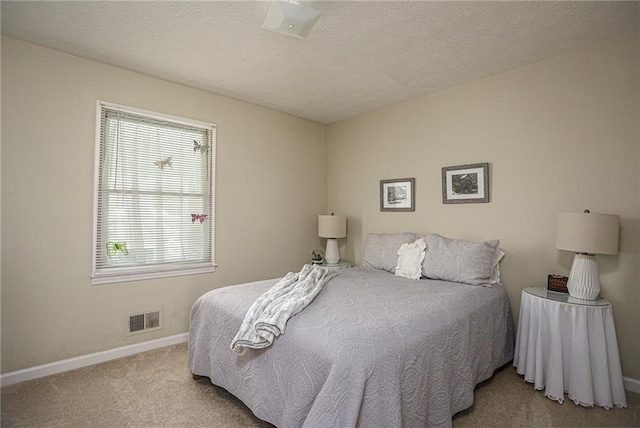 bedroom with a textured ceiling and light colored carpet