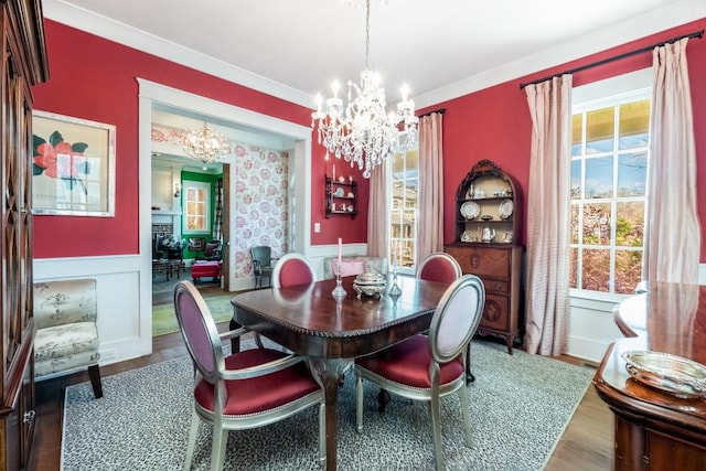 dining room featuring crown molding, a healthy amount of sunlight, an inviting chandelier, and wood-type flooring