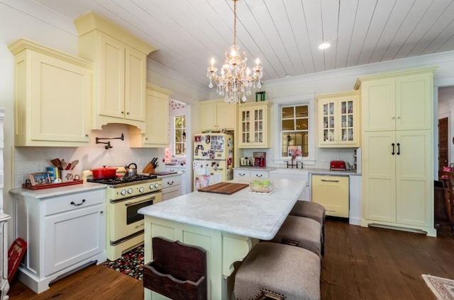 kitchen featuring a kitchen island, dark hardwood / wood-style floors, white appliances, pendant lighting, and a chandelier