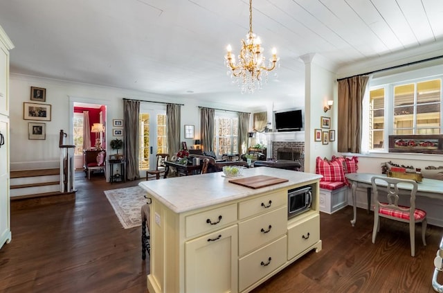 kitchen with pendant lighting, stainless steel microwave, dark hardwood / wood-style flooring, and a fireplace