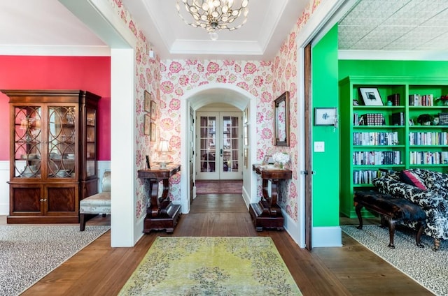 foyer entrance with ornamental molding, french doors, a notable chandelier, and dark hardwood / wood-style floors